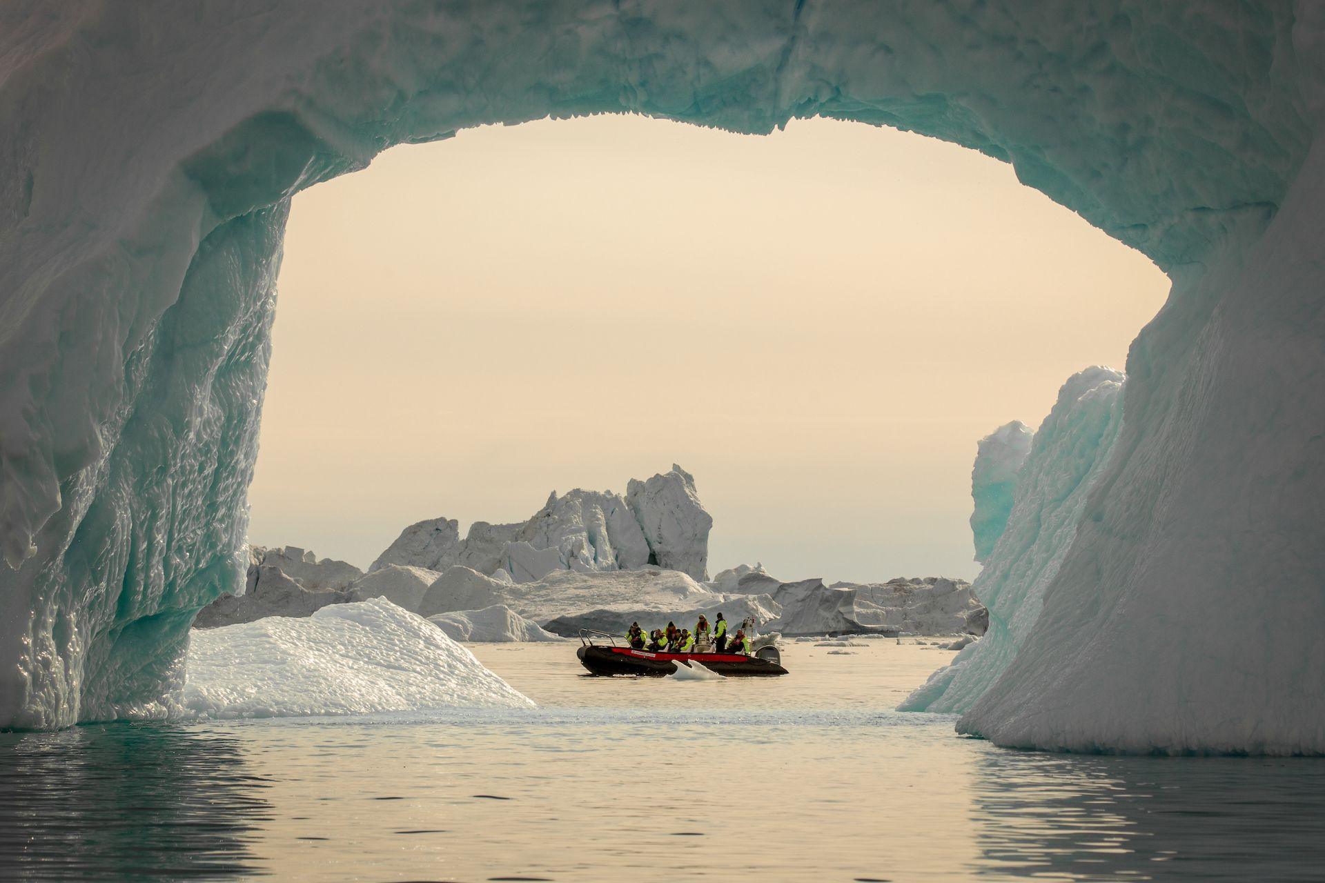 A boat seen through an iceberg arc in the Disko Bay, Greenland
